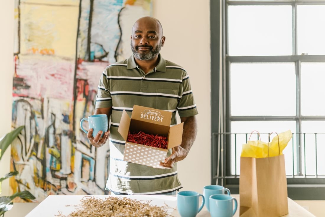 Emprendedor empacando una caja de regalo con tazas