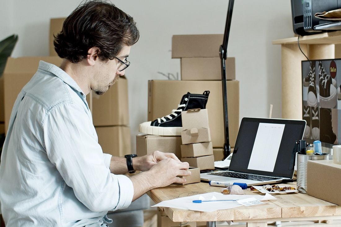 Emprendedor armando un pedido de zapatillas frente a su computador