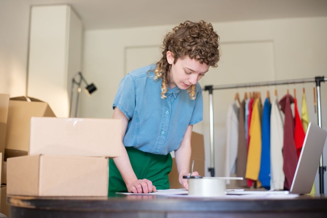 Emprendedora organizando pedidos sobre una mesa con cajas de envío