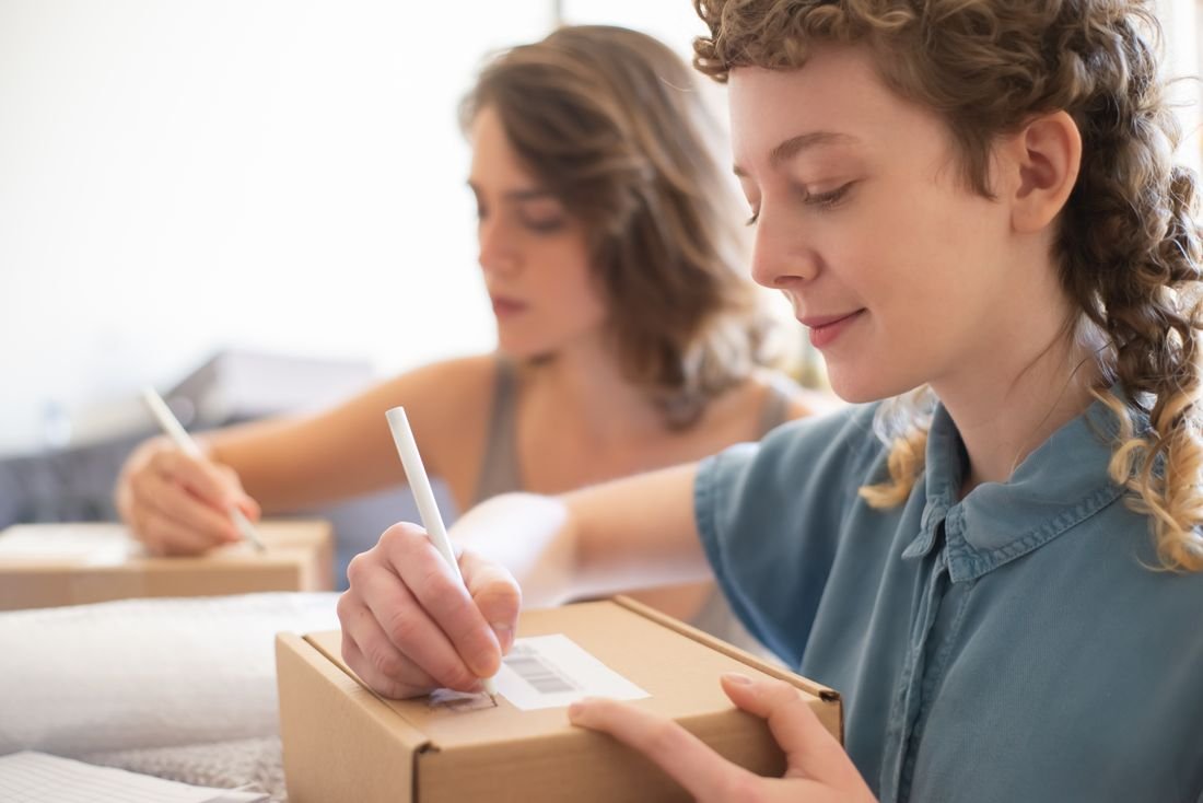 Dos emprendedoras rotulando cajas de envío